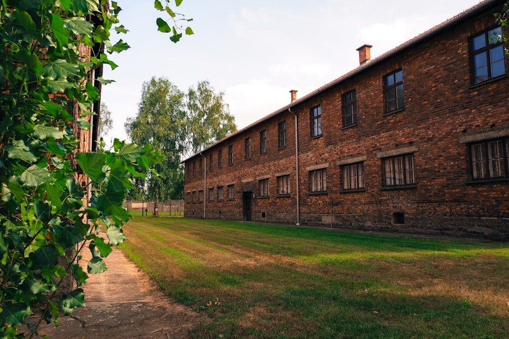 an old brick building with a grassy field in front of it