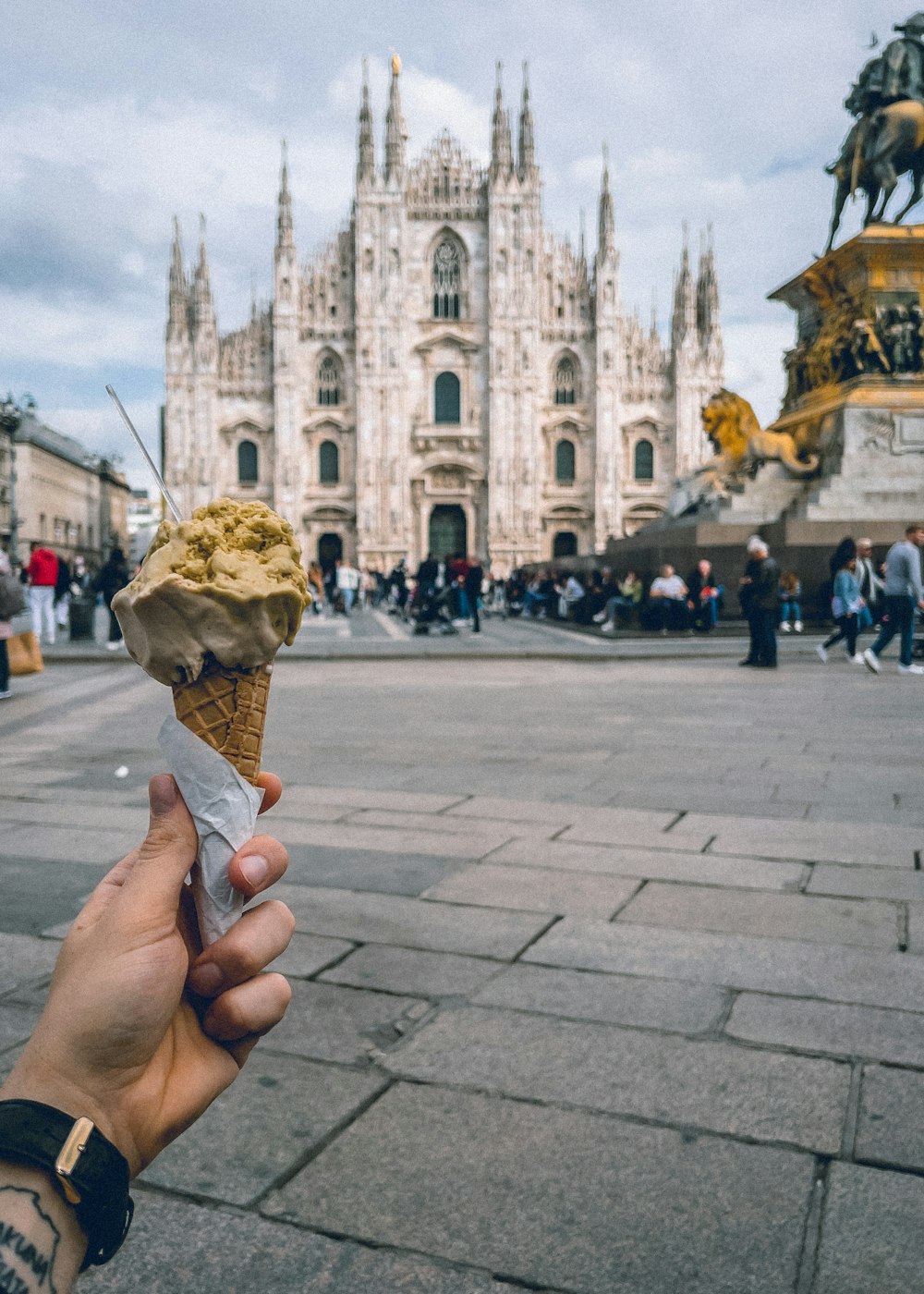 a hand holding an ice cream cone in front of a cathedral