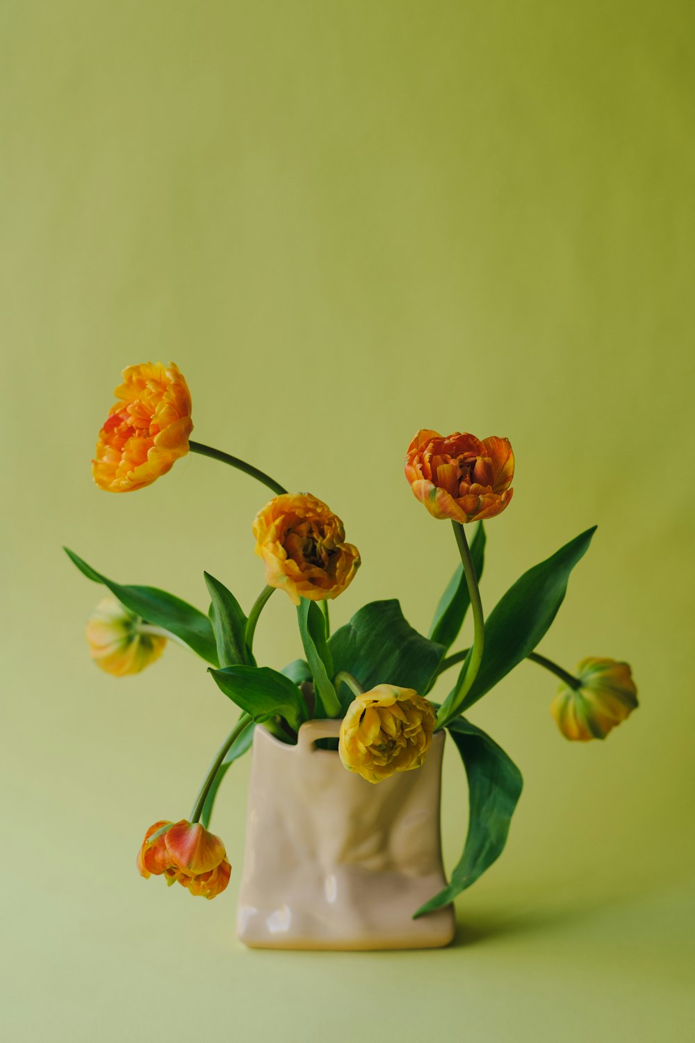 a vase with yellow and orange flowers in it