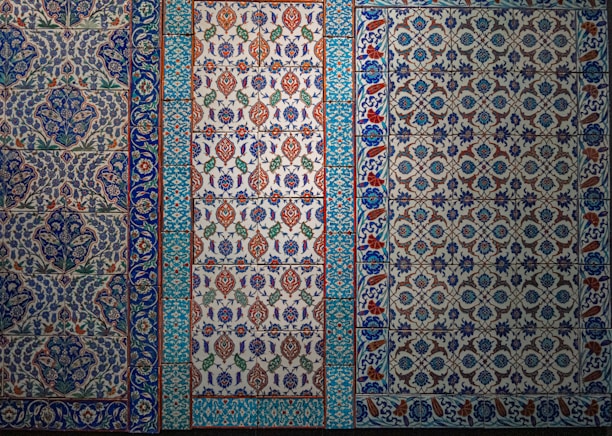 The image features a series of intricately designed tiles with intricate floral and geometric patterns. The tiles display a variety of colors, predominantly featuring blues, whites, reds, and greens with elaborate motifs and symmetrical designs.