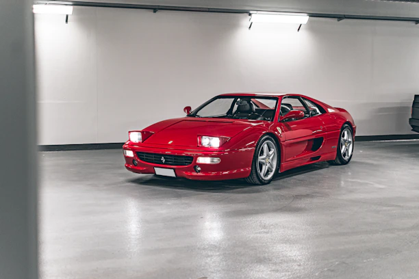 A sleek, red performance car parked inside a modern, well-lit auto repair garage.