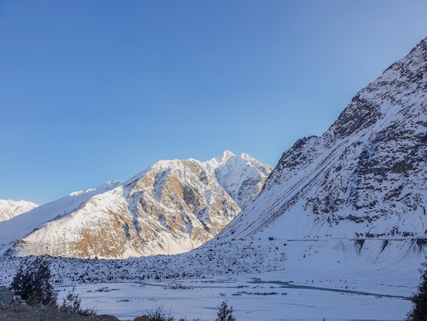 A serene mountain landscape with snow-capped peaks under a clear blue sky.