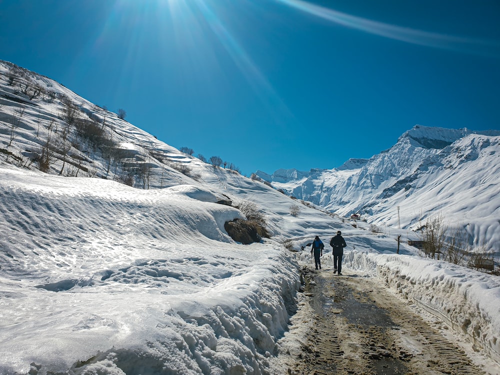 a couple of people walking down a snow covered road