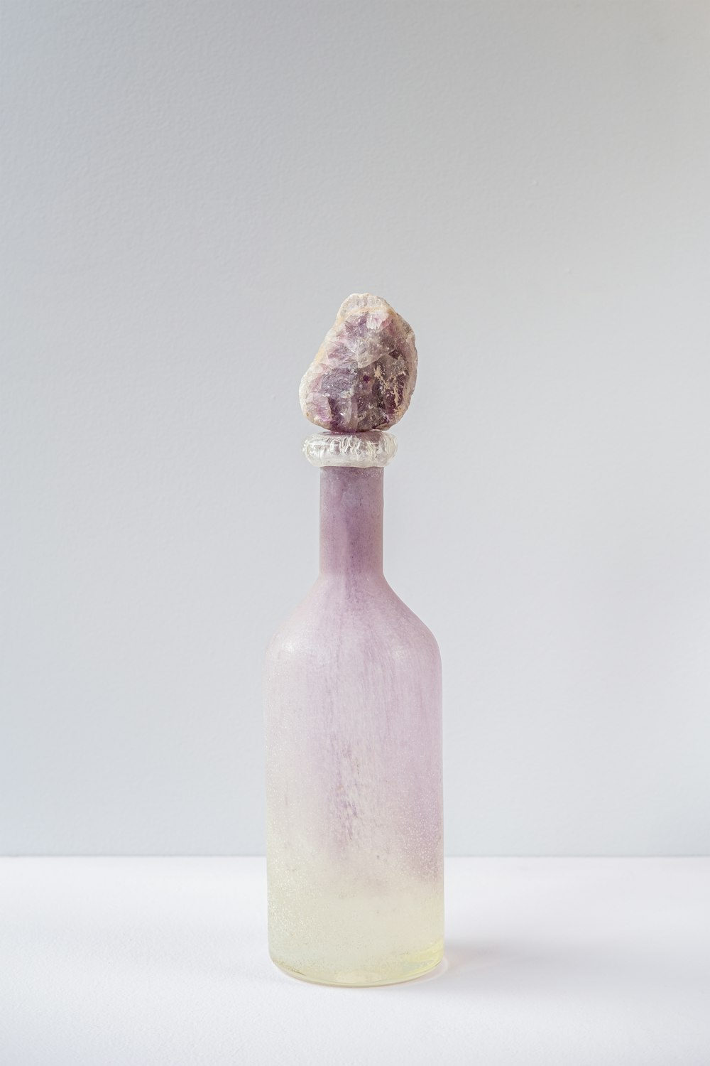 a bottle with a rock in it sitting on a table
