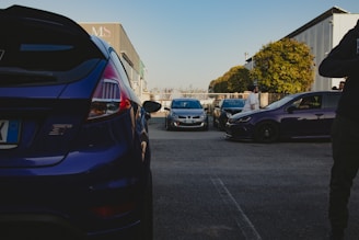 A busy car export yard with various used cars ready for shipment under clear skies.