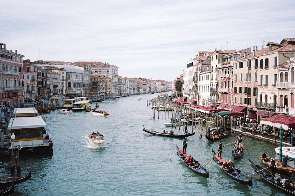 a group of boats floating down a river next to tall buildings