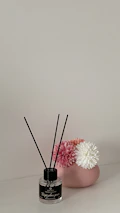 A minimalist modern setup with a scented candle and design elements in green, beige, and soft pink hues.