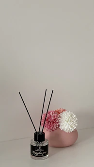 A minimalist modern setup with a scented candle and design elements in green, beige, and soft pink hues.