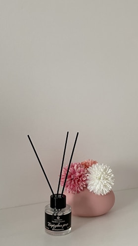 A minimalist vanity setup featuring marvello perfume bottles alongside a small vase of fresh flowers and a leather-bound journal.