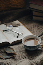 A shelf filled with books, with a steaming cup of coffee and a glass of chach placed nearby.