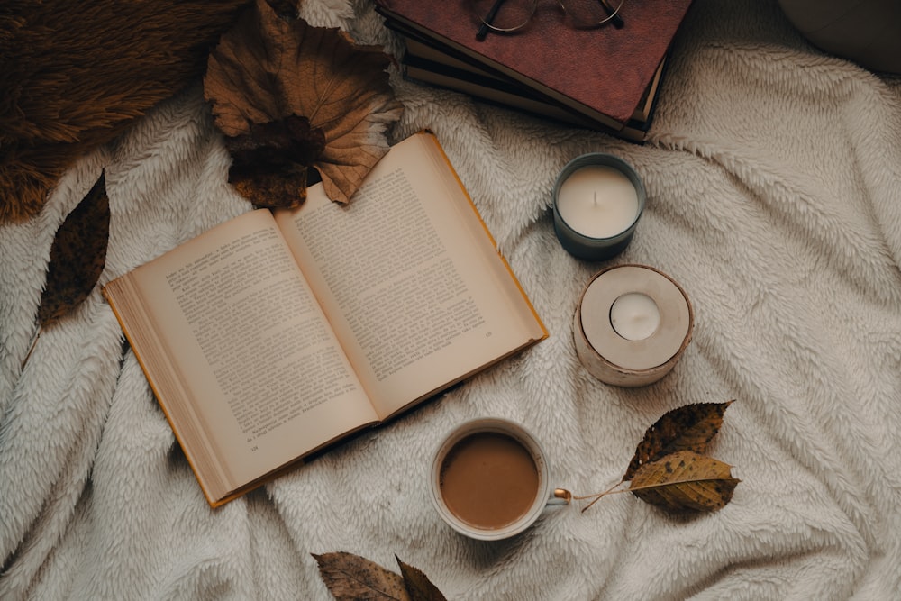 an open book and two cups of coffee on a blanket