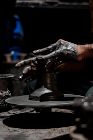 An artisan’s hands shaping clay on a potter’s wheel, surrounded by finished pieces glowing in natural light.