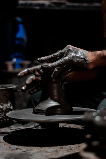 A close-up shot of artisan hands shaping intricate Moroccan pottery under warm studio lighting.