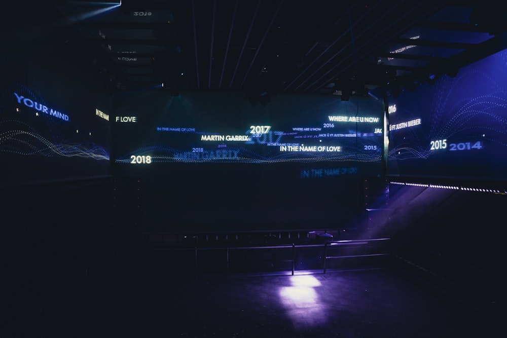 a dark room with blue lights and a large screen