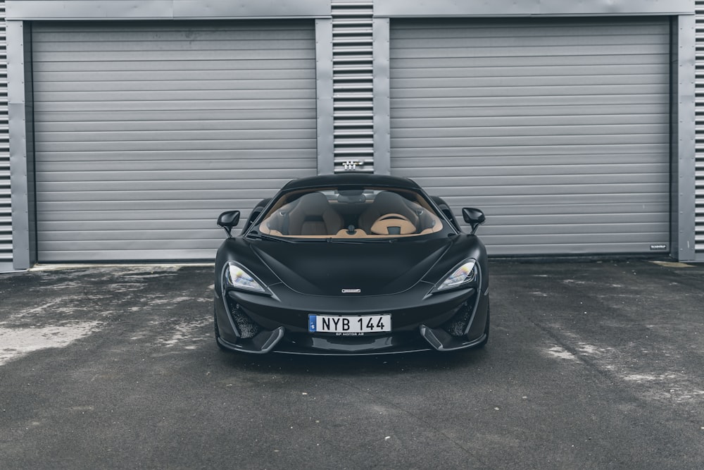 a black sports car parked in front of a garage