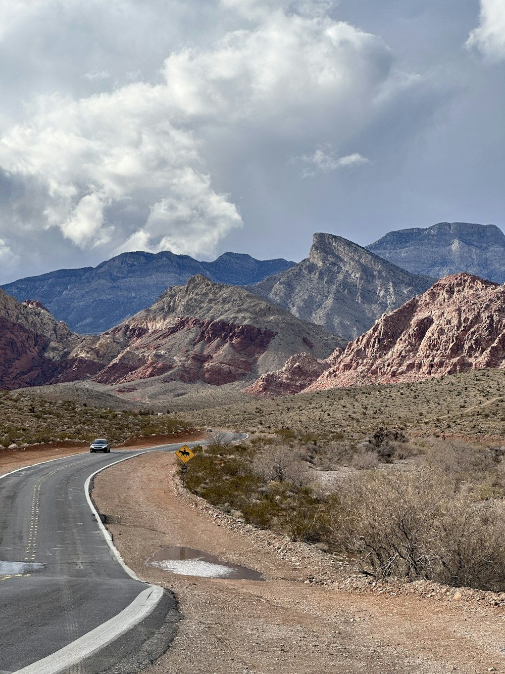 a car driving down a road with mountains in the background