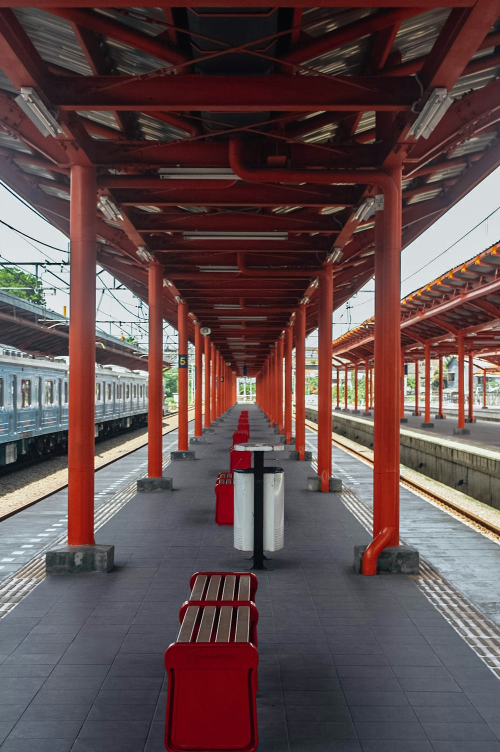 Una fila de bancos rojos sentados al lado de una estación de tren