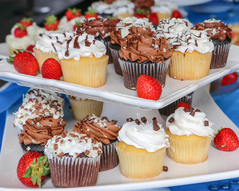 three trays of cupcakes with chocolate frosting and strawberries