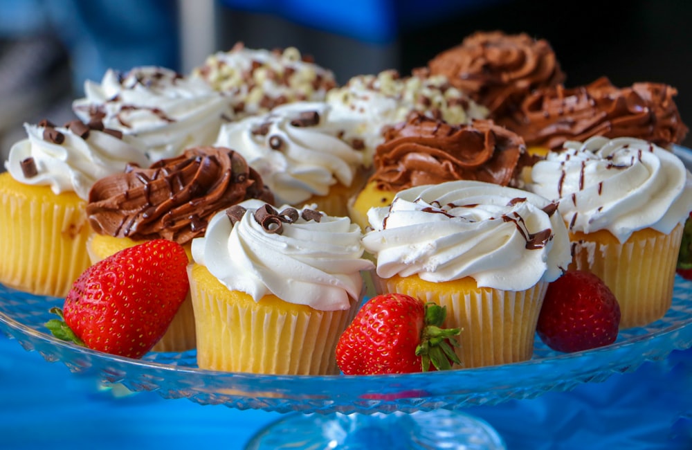 a plate of cupcakes with chocolate frosting and strawberries