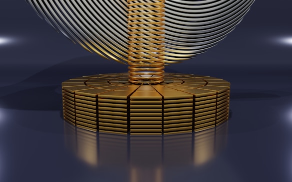 A futuristic, abstract design featuring a series of stacked golden disks forming a circular base. Rising from the center is a column of tightly coiled golden rings, with a large, swirling metallic structure resembling a helix or wave, hovering above. The image has a sleek, polished appearance with reflective surfaces and soft lighting.