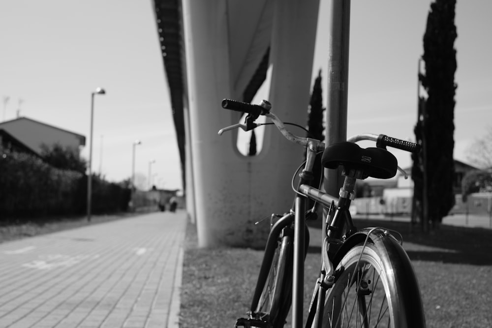 a black and white photo of a bike parked next to a building
