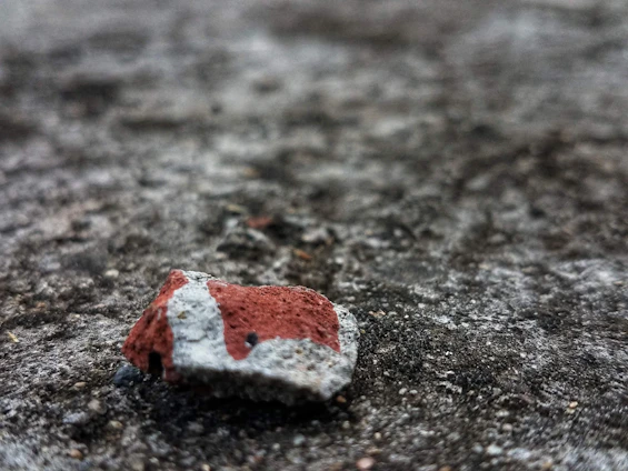 A close-up of a handmade concrete Texas-shaped stone resting on a weathered wooden table, sunlight casting warm shadows.