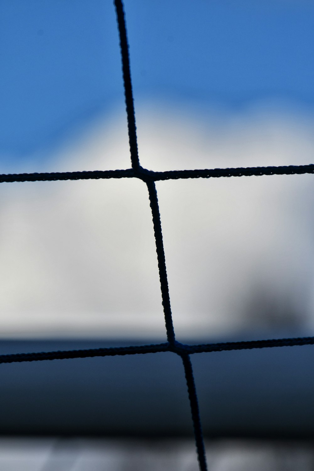 a close up of a wire fence with a sky in the background