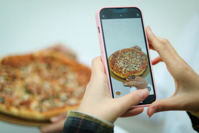 Close-up of a hand holding a phone with pizza menu on screen.