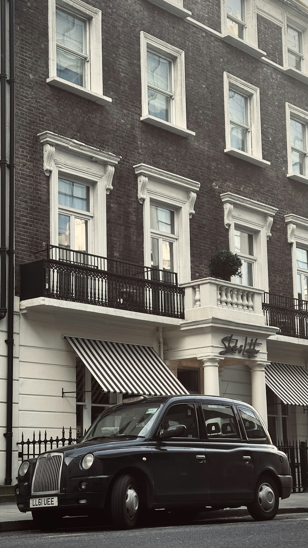 a black car parked in front of a tall building