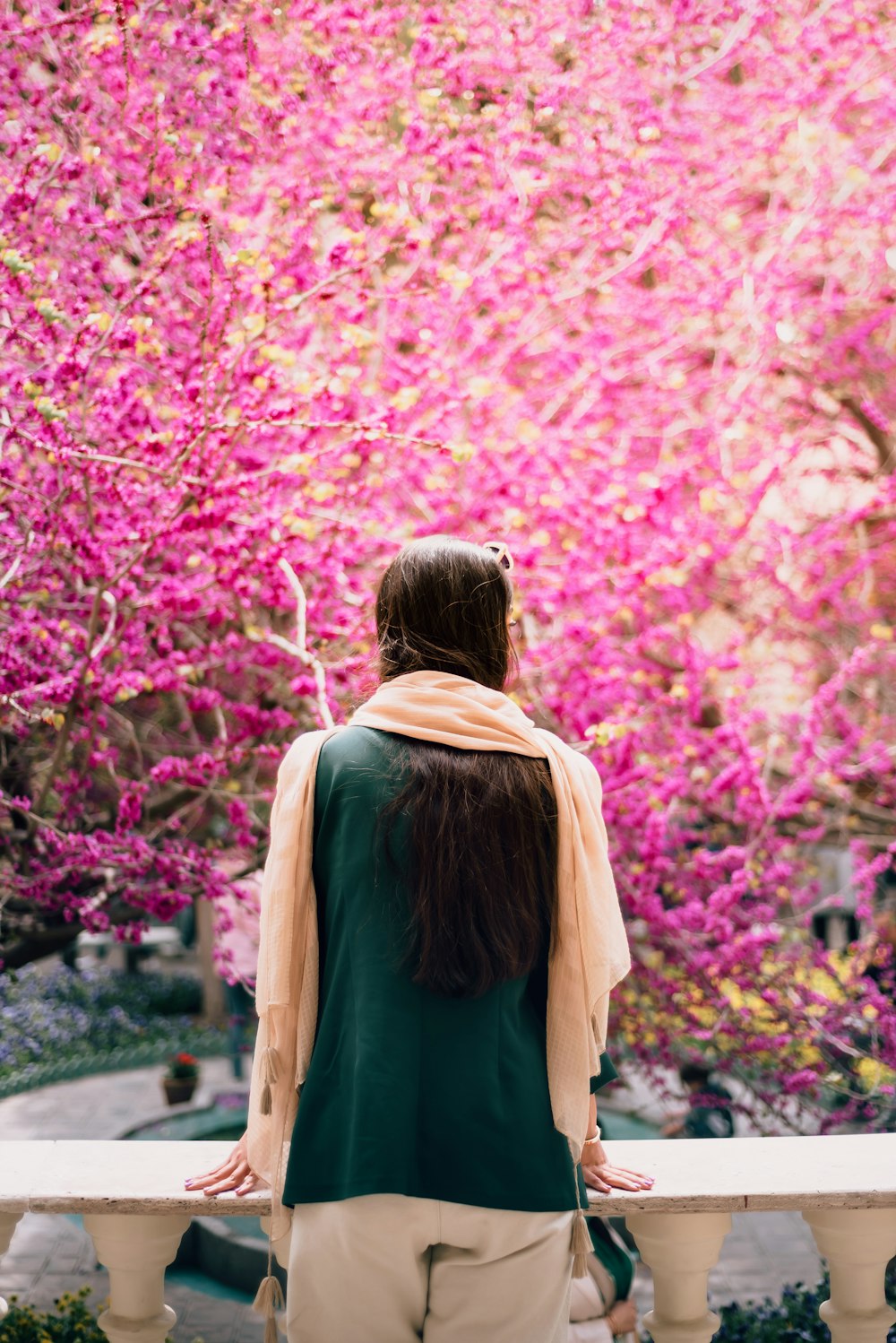 a woman sitting on a bench in front of a pink tree