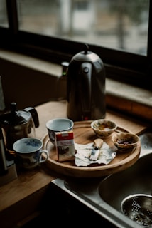 An electric kettle displayed on a rustic wooden table with fresh herbs and tea leaves nearby.