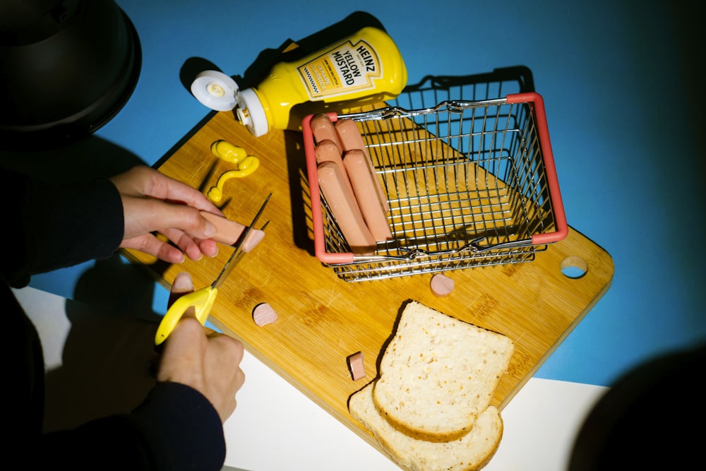 a person cutting a hot dog on a cutting board