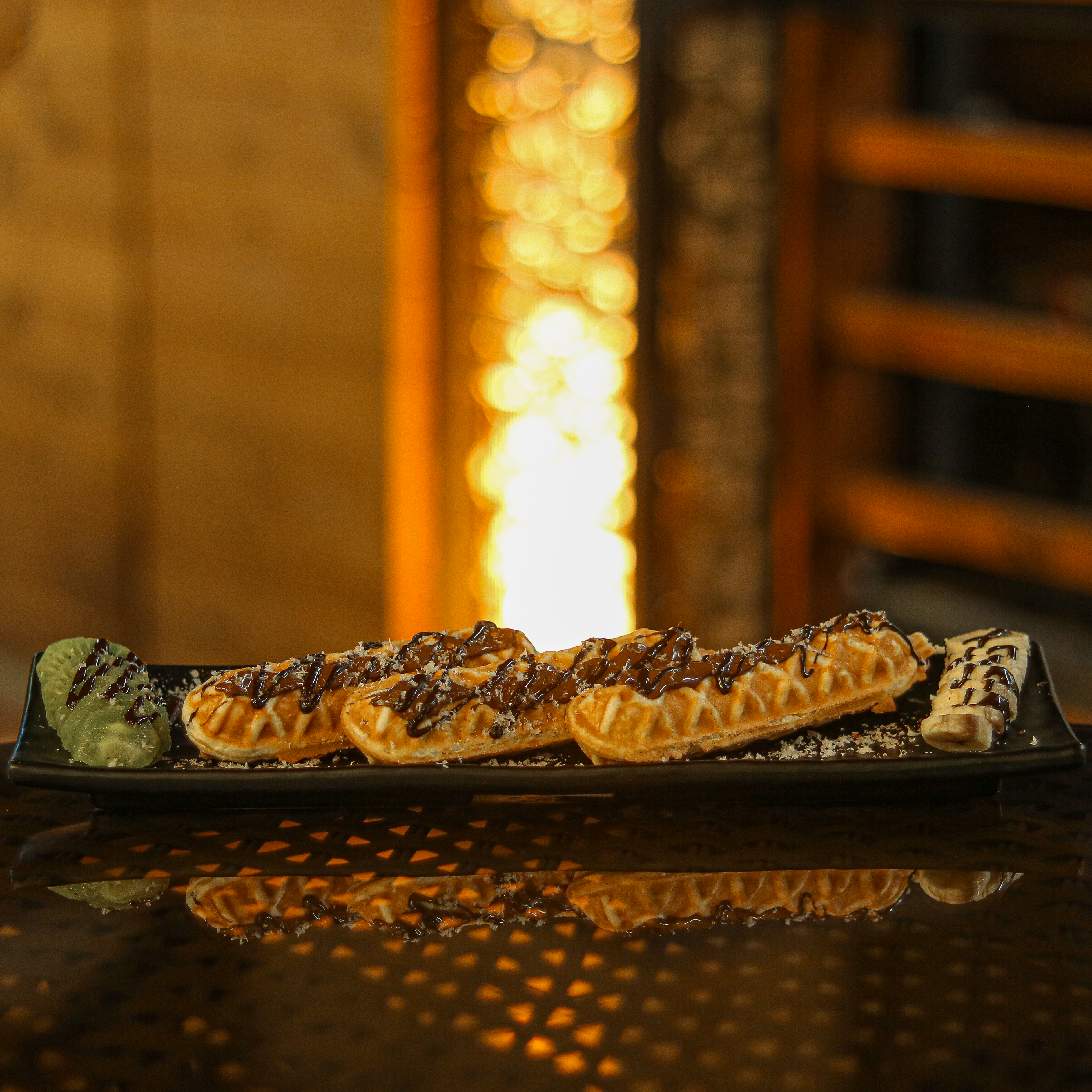 a black plate topped with waffles covered in toppings