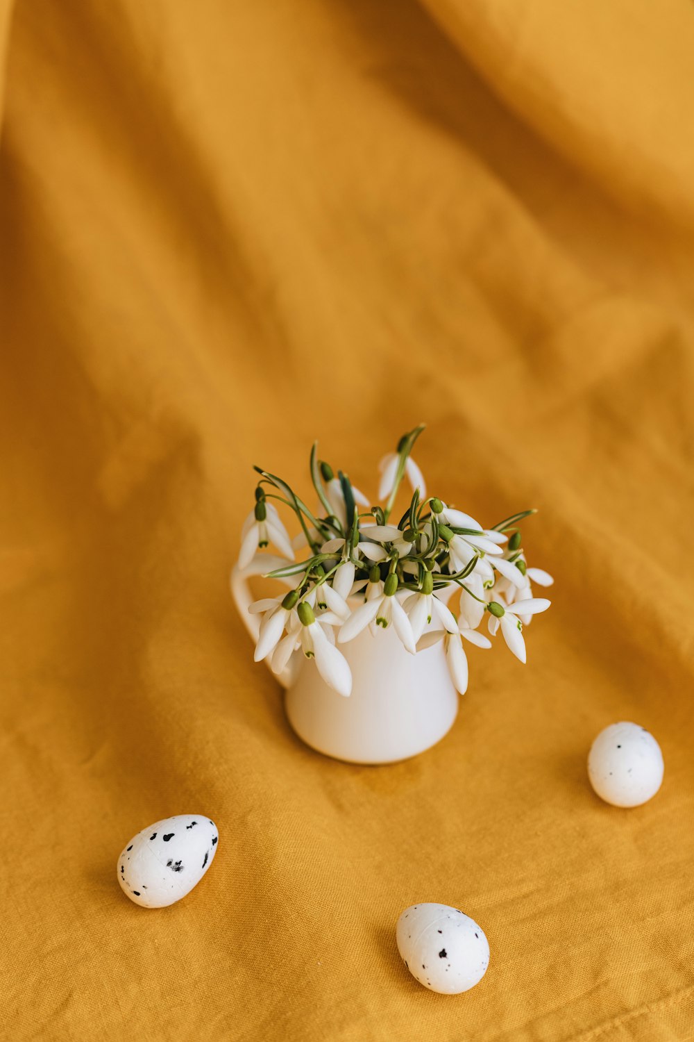 a white vase filled with flowers and eggs