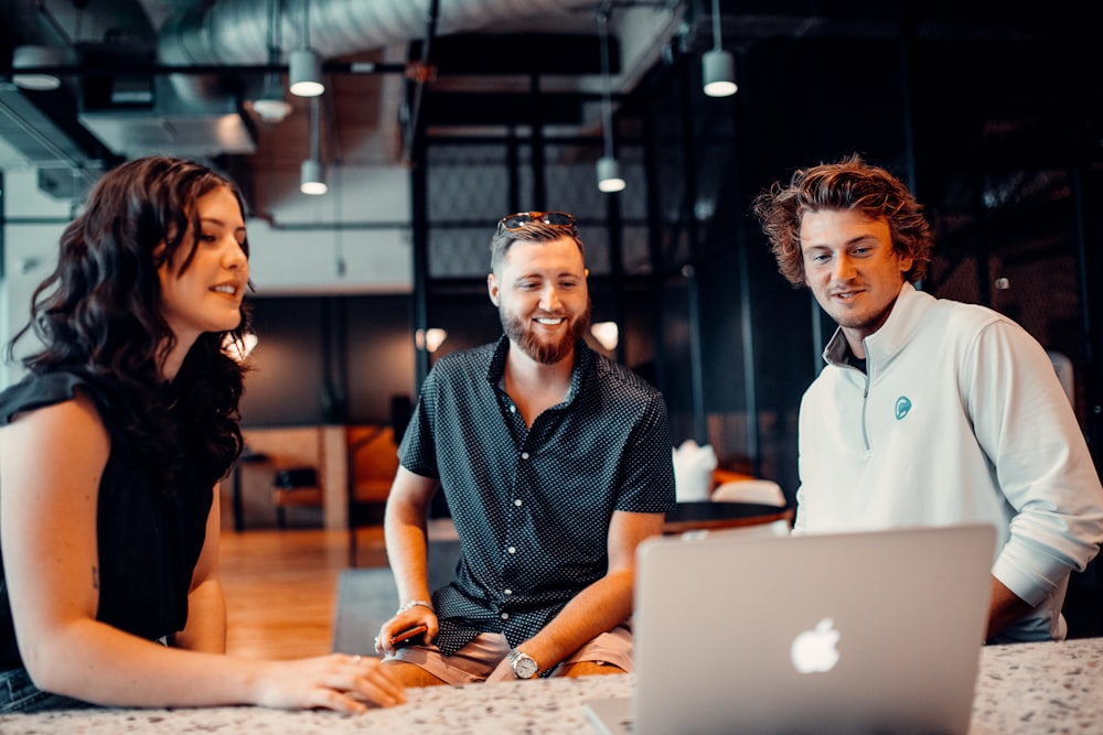 a group of people sitting around a laptop computer