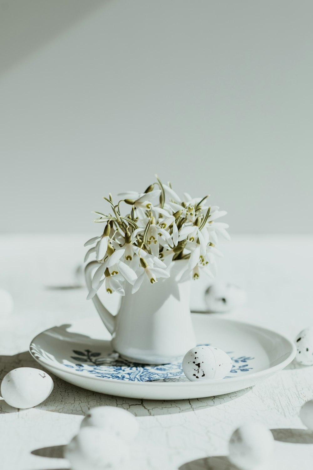 a white vase filled with flowers on top of a plate