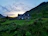 Cozy medieval stone cottage surrounded by lush greenery at sunset.