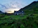 Cozy medieval stone cottage surrounded by lush greenery at sunset.