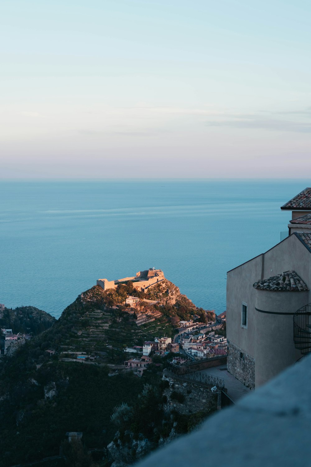 a view of a castle on a hill with the ocean in the background