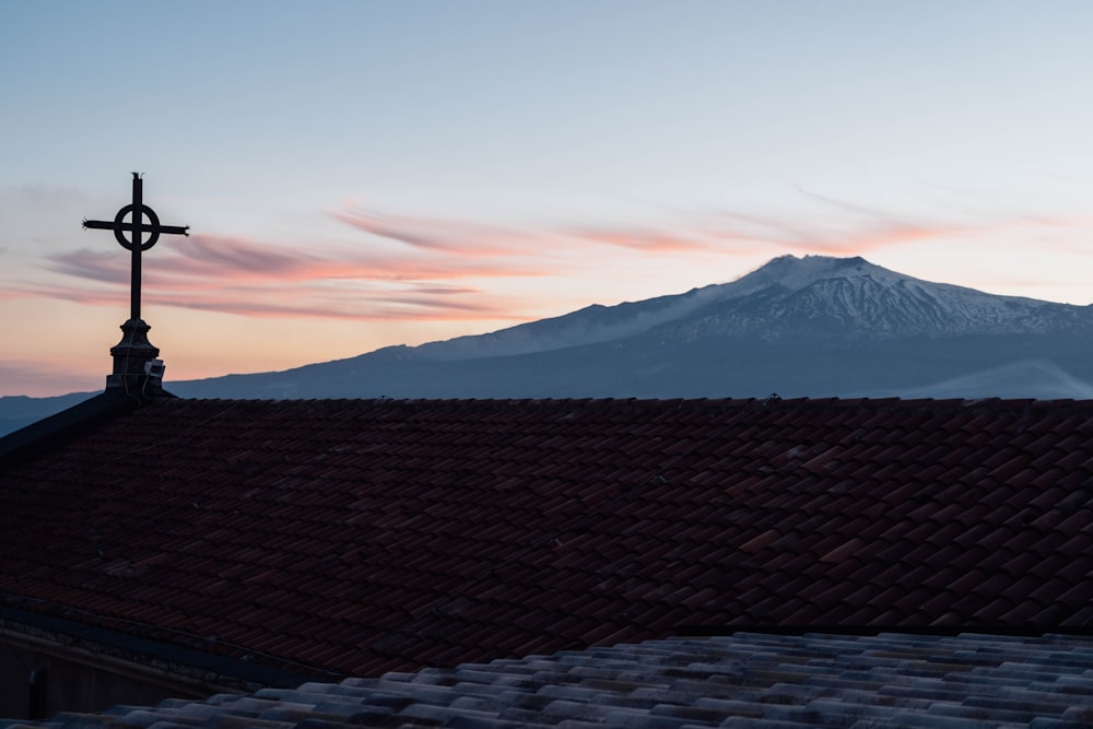 a cross on top of a building with a mountain in the background