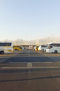 A lineup of various sized coaches from 12 to 74 seats parked in front of Heathrow Airport terminals under a clear sky