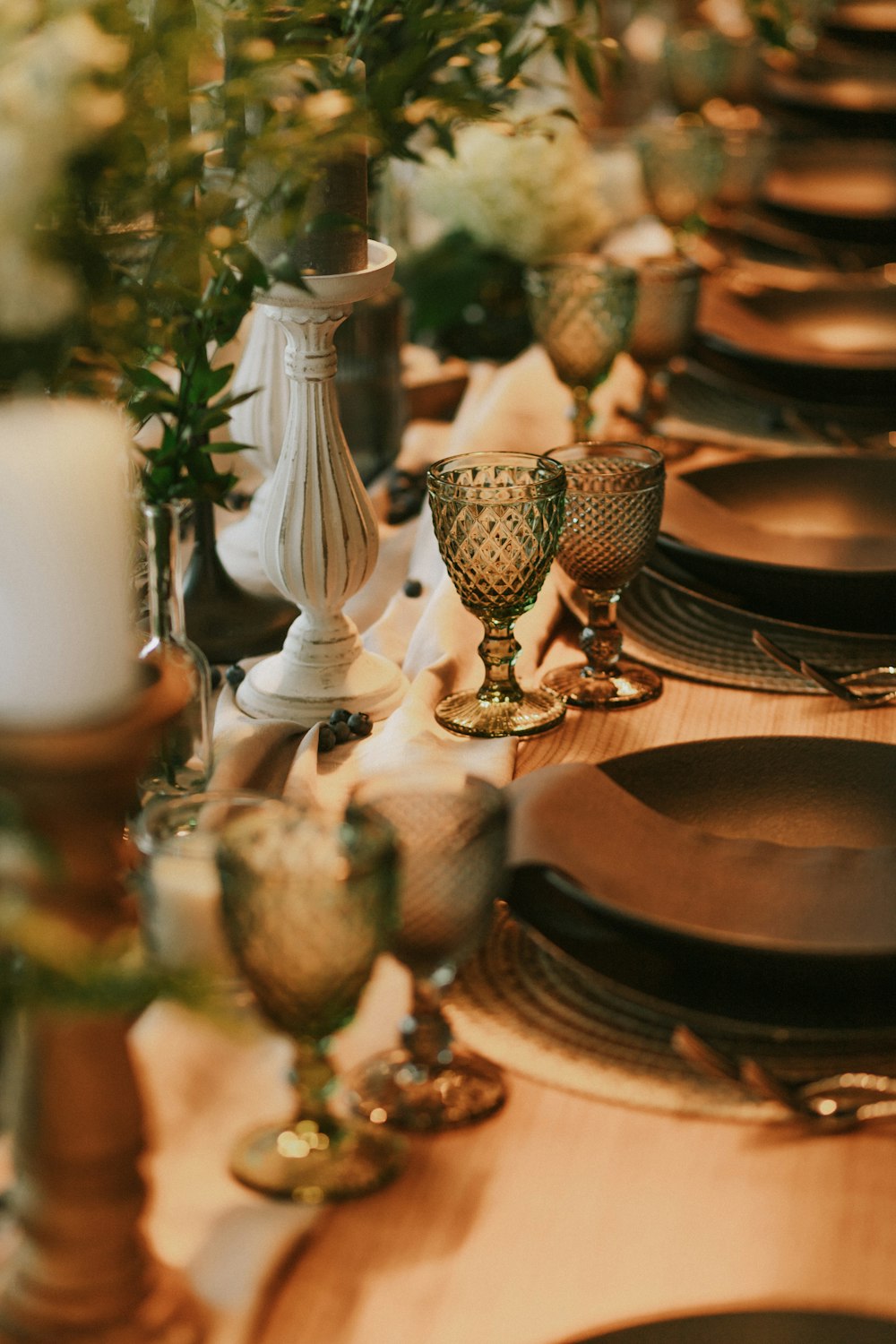 a table set for a formal dinner with plates and vases