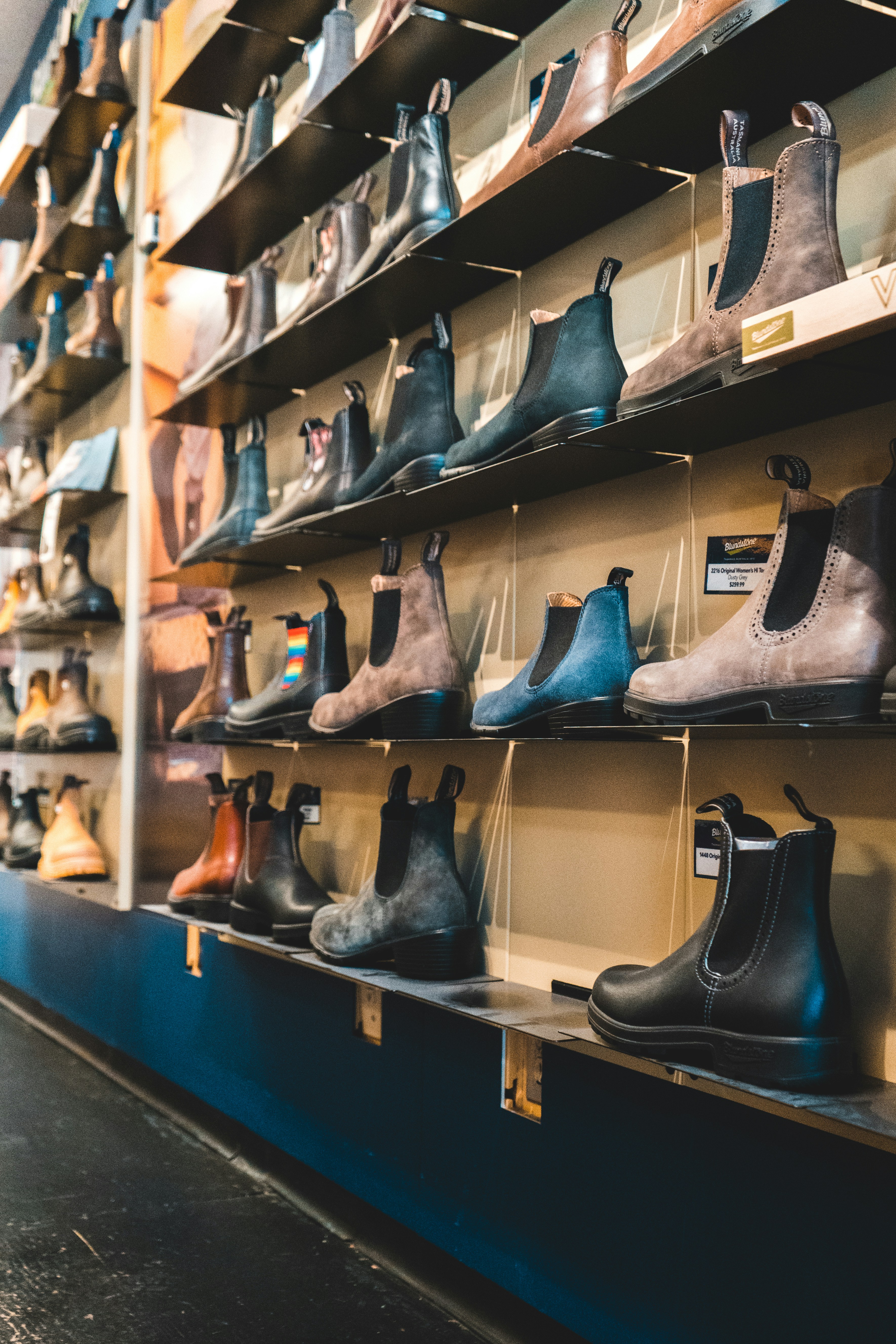 Blundstone boots displayed on dark retail shelves in various colors.