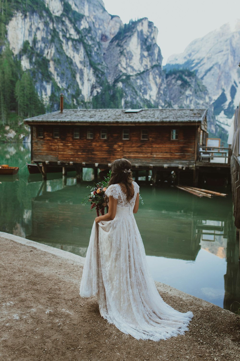 a woman in a wedding dress standing by a lake