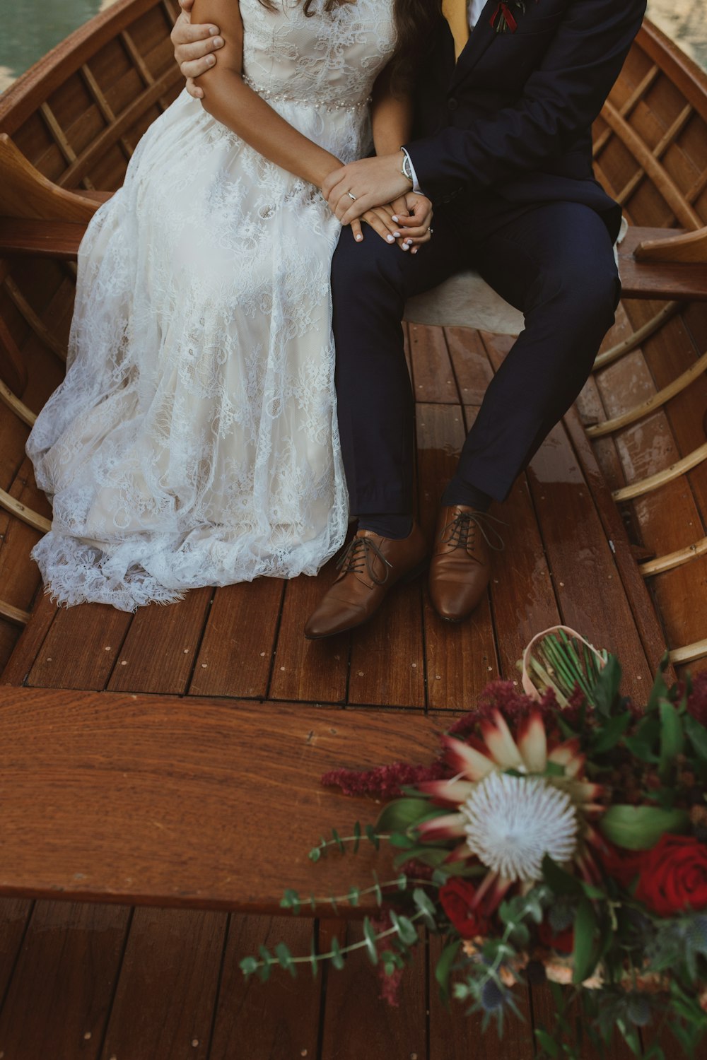 a bride and groom sitting on a boat in the water