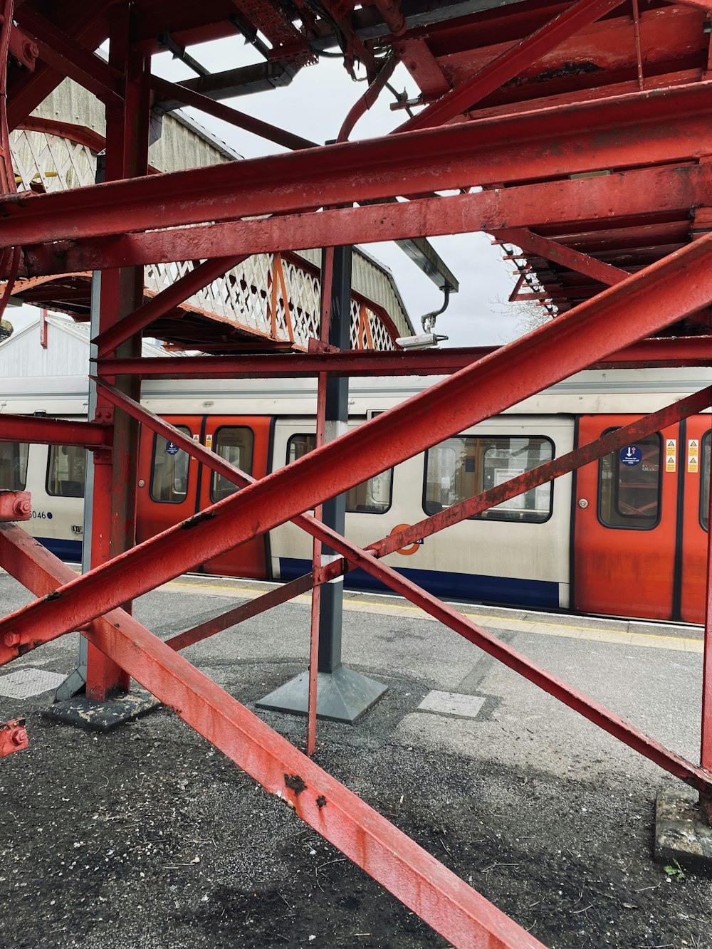 a red metal structure with a train in the background