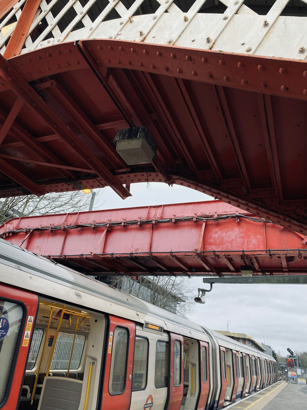 a red and white train passing under a bridge