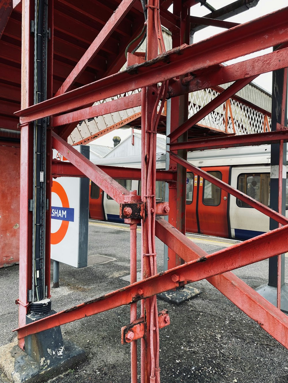 Una estructura metálica roja con un tren al fondo