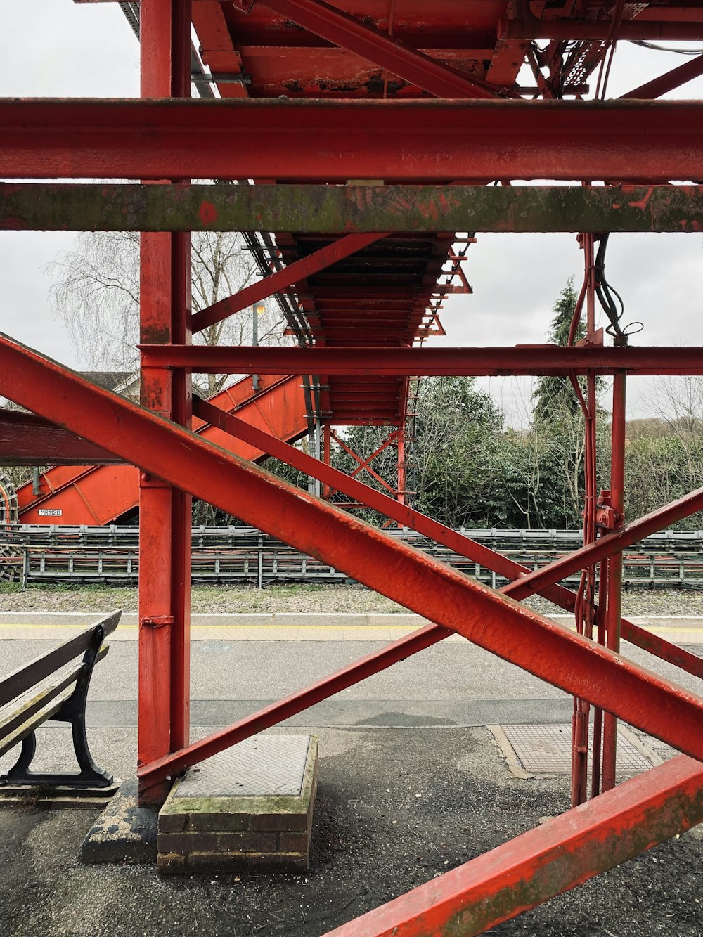 a red metal structure with a bench underneath it