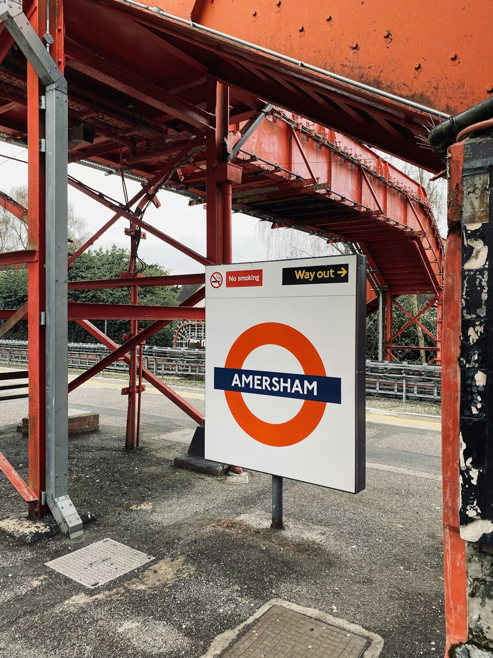 an orange and white sign sitting under a bridge